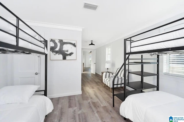 bedroom with wood-type flooring and ornamental molding