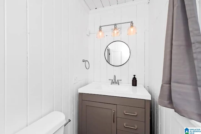 bathroom with vanity, toilet, and wooden walls