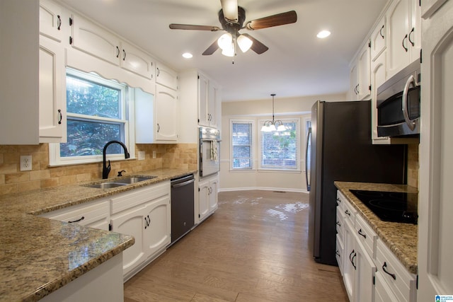 kitchen featuring white cabinets, light stone counters, sink, and appliances with stainless steel finishes