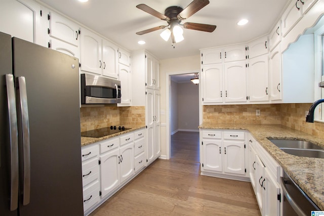 kitchen featuring light stone countertops, sink, stainless steel appliances, backsplash, and white cabinets