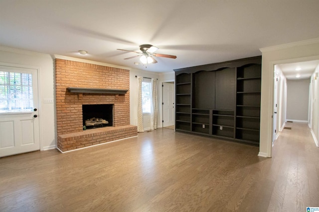 unfurnished living room with a fireplace, hardwood / wood-style flooring, ceiling fan, and crown molding