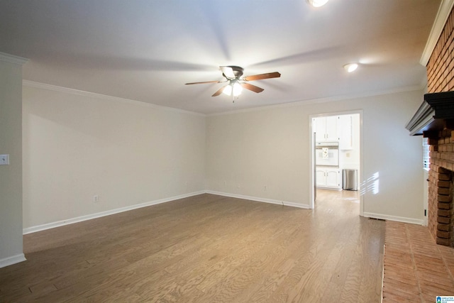 unfurnished living room featuring hardwood / wood-style floors, ceiling fan, ornamental molding, and a brick fireplace