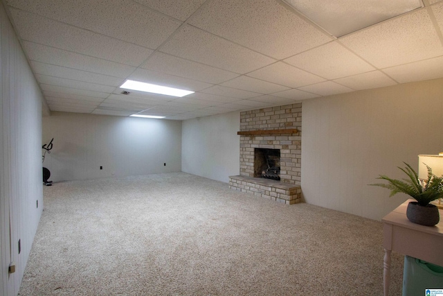 basement featuring a paneled ceiling, carpet floors, and a brick fireplace