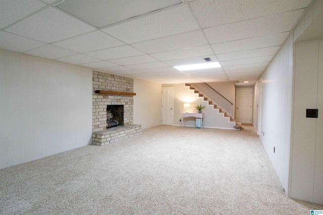 basement with carpet, a paneled ceiling, and a brick fireplace