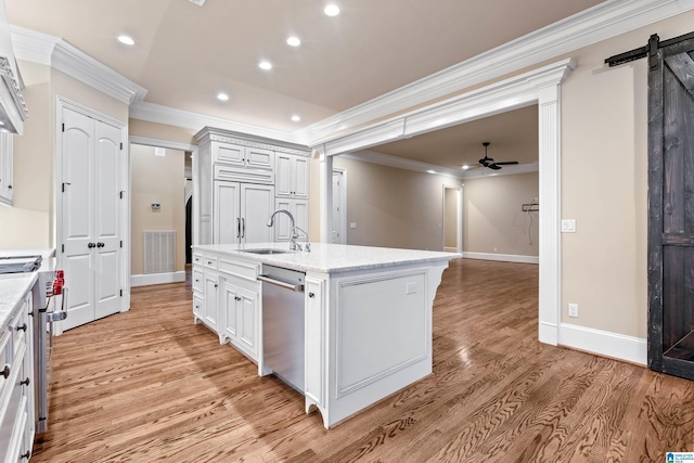 kitchen featuring appliances with stainless steel finishes, ceiling fan, a kitchen island with sink, sink, and a barn door