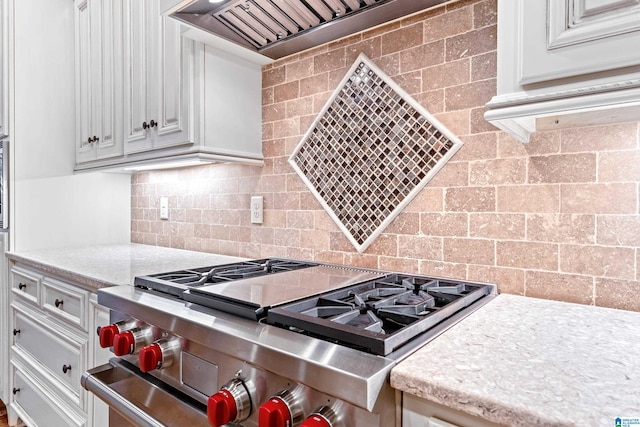 kitchen featuring backsplash, white cabinetry, stainless steel range oven, and premium range hood