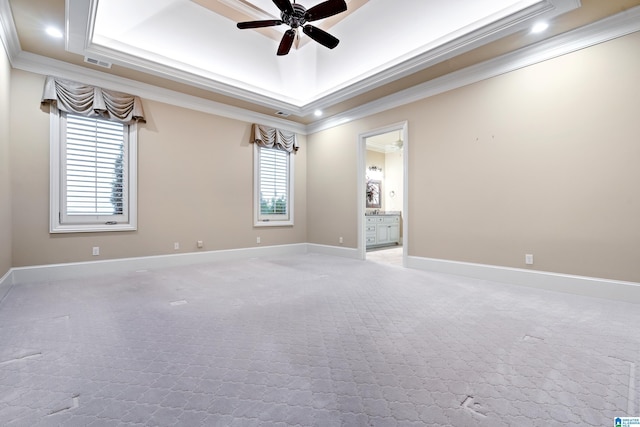 spare room with a raised ceiling, plenty of natural light, and ornamental molding