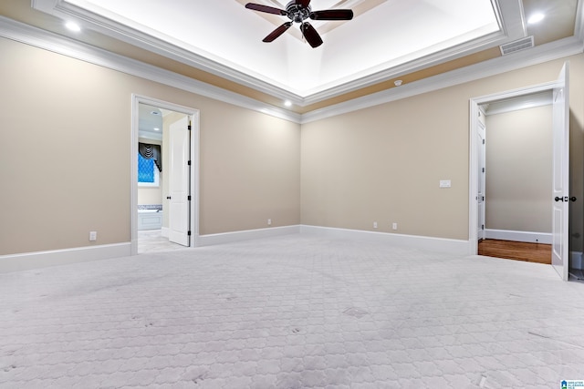 spare room featuring light colored carpet, a raised ceiling, ceiling fan, and ornamental molding