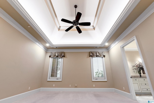 spare room featuring a tray ceiling, light carpet, crown molding, and ceiling fan