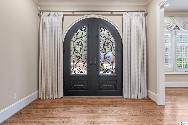 foyer entrance featuring crown molding, french doors, and hardwood / wood-style floors