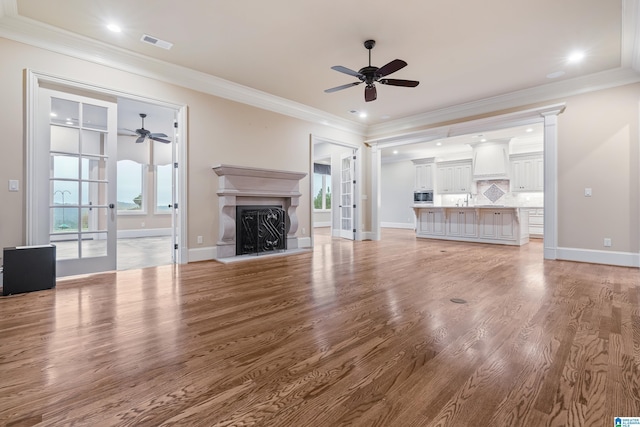 unfurnished living room featuring light wood-type flooring, crown molding, and french doors