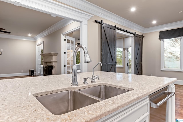 kitchen with a barn door, hardwood / wood-style flooring, crown molding, and sink