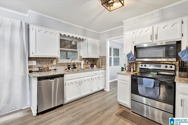 kitchen with white cabinets, stainless steel appliances, light stone countertops, and sink