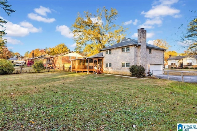 rear view of property featuring a lawn, a sunroom, and a garage