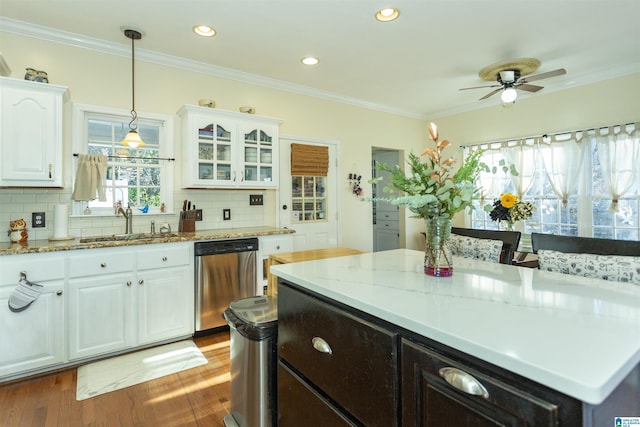 kitchen with decorative backsplash, light stone counters, stainless steel dishwasher, sink, and white cabinets