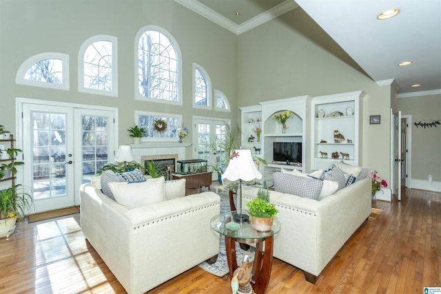 living room featuring crown molding, light hardwood / wood-style flooring, a high ceiling, and french doors