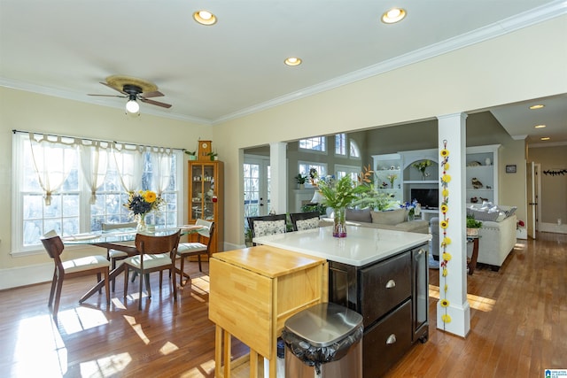 kitchen with ornate columns, ceiling fan, crown molding, and wood-type flooring