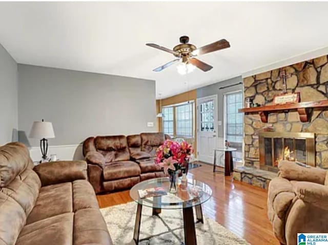 living room with ceiling fan, a fireplace, and light hardwood / wood-style flooring