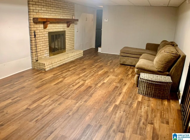 living room with a fireplace, hardwood / wood-style flooring, and a drop ceiling