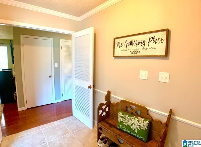 corridor with crown molding, light tile patterned floors, and a textured ceiling