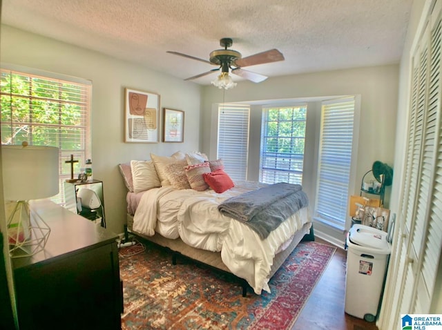 bedroom with ceiling fan, a closet, dark wood-type flooring, and a textured ceiling