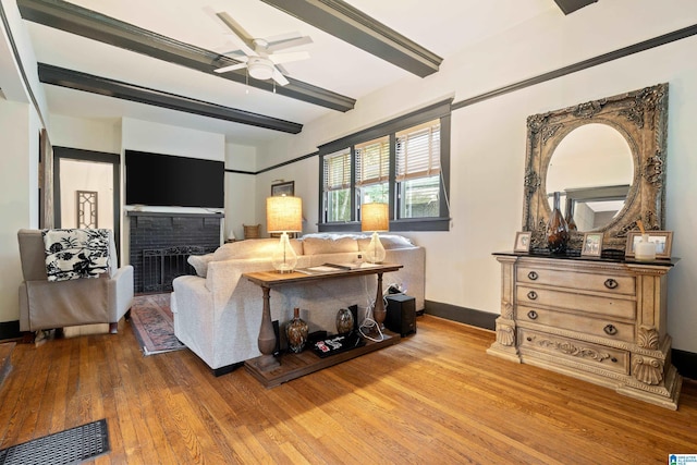 living room with beam ceiling, ceiling fan, hardwood / wood-style floors, and a brick fireplace