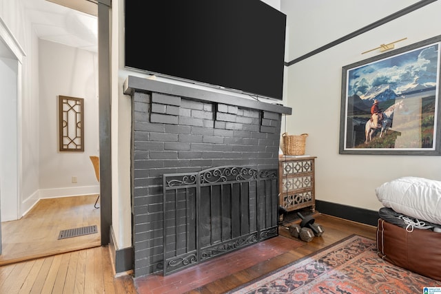 bedroom with a brick fireplace and hardwood / wood-style flooring