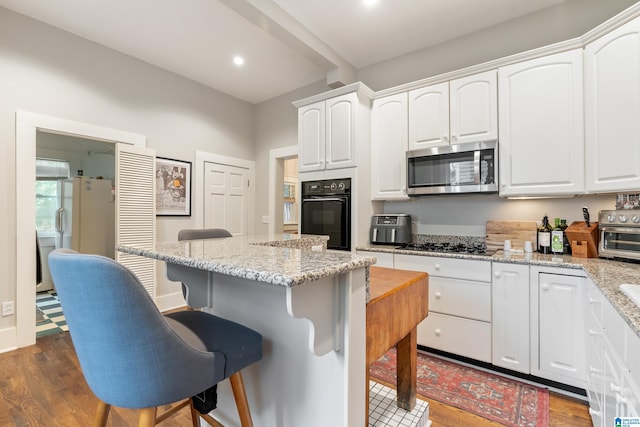 kitchen featuring white cabinets, appliances with stainless steel finishes, dark hardwood / wood-style flooring, and light stone counters