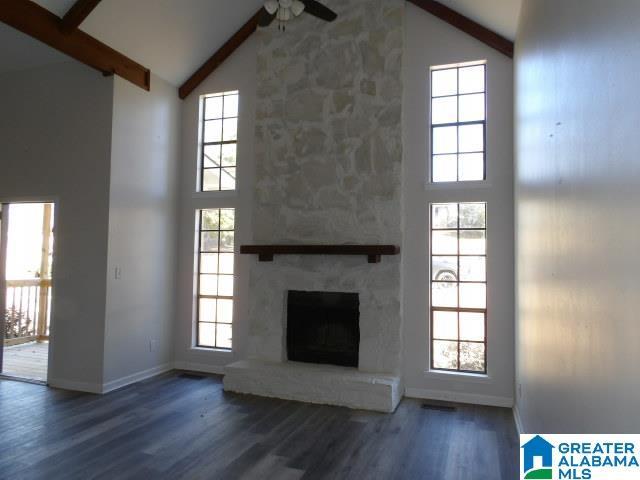 unfurnished living room featuring a large fireplace, ceiling fan, a healthy amount of sunlight, beam ceiling, and high vaulted ceiling