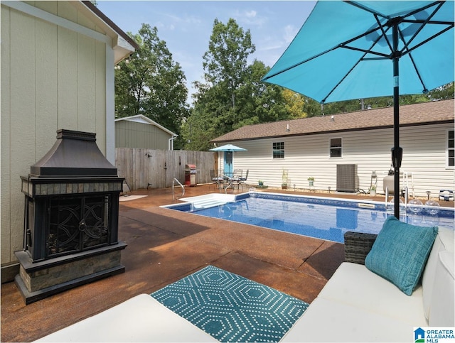 view of swimming pool featuring a patio area and exterior fireplace