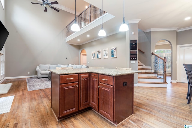 kitchen with ceiling fan, a center island, pendant lighting, and ornamental molding