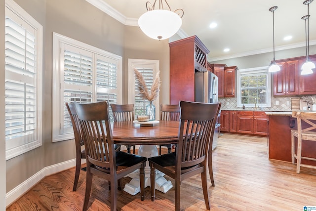 dining room featuring sink, light hardwood / wood-style floors, and ornamental molding