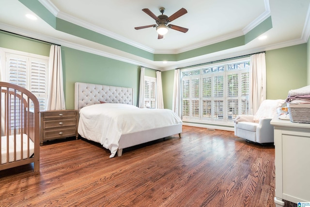 bedroom with a tray ceiling, ceiling fan, crown molding, and dark hardwood / wood-style floors