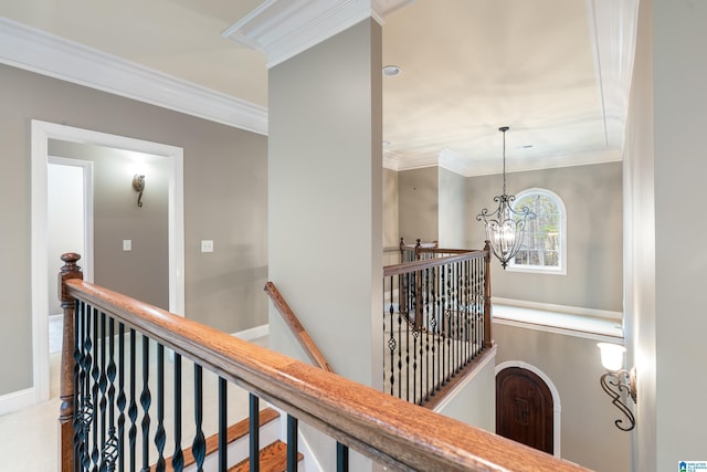 hall with ornamental molding and a chandelier