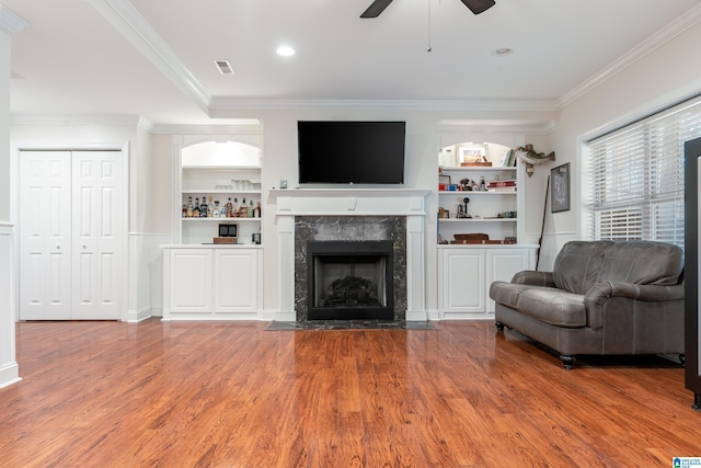 living room with wood-type flooring, ceiling fan, and crown molding