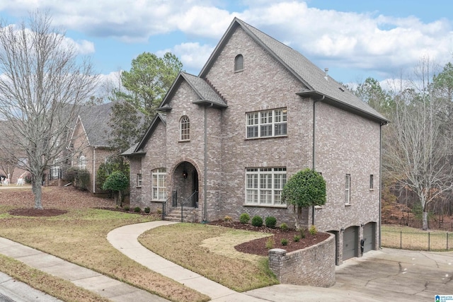 french country inspired facade featuring a front yard and a garage