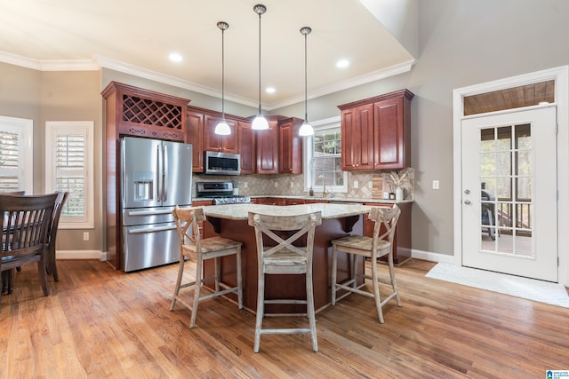 kitchen with sink, hanging light fixtures, stainless steel appliances, light stone counters, and backsplash