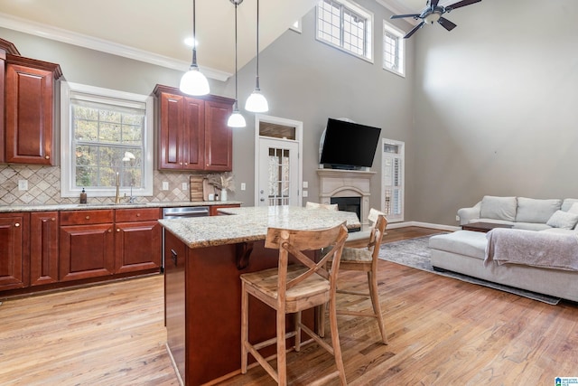 kitchen with pendant lighting, a kitchen breakfast bar, sink, decorative backsplash, and ornamental molding