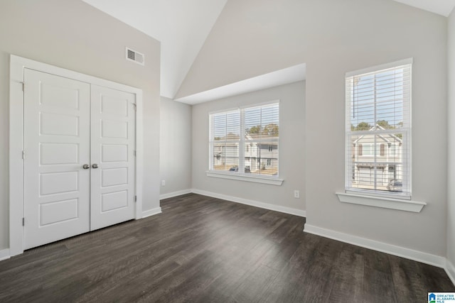 unfurnished bedroom with dark hardwood / wood-style flooring, lofted ceiling, and a closet