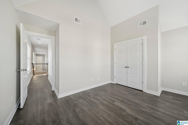 unfurnished bedroom featuring dark wood-type flooring, high vaulted ceiling, and a closet