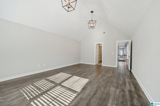 unfurnished living room with dark wood-type flooring, vaulted ceiling, and a notable chandelier