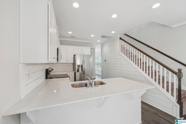 kitchen featuring kitchen peninsula, stainless steel refrigerator with ice dispenser, electric stove, white cabinetry, and a breakfast bar area