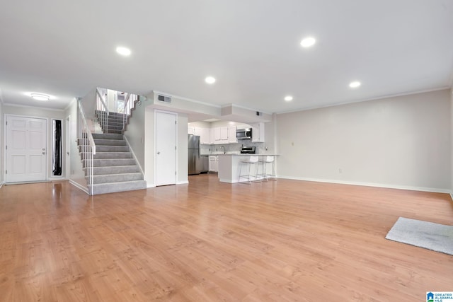 unfurnished living room with sink, light wood-type flooring, and crown molding