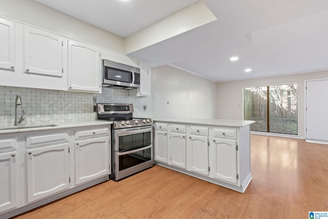 kitchen featuring white cabinets, sink, light hardwood / wood-style flooring, decorative backsplash, and stainless steel appliances