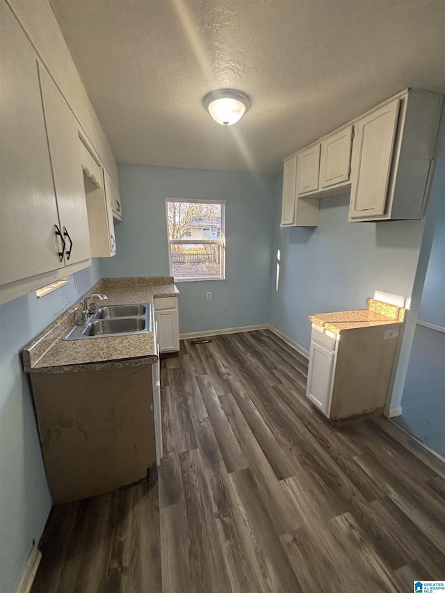 kitchen with a textured ceiling, dark hardwood / wood-style floors, white cabinetry, and sink