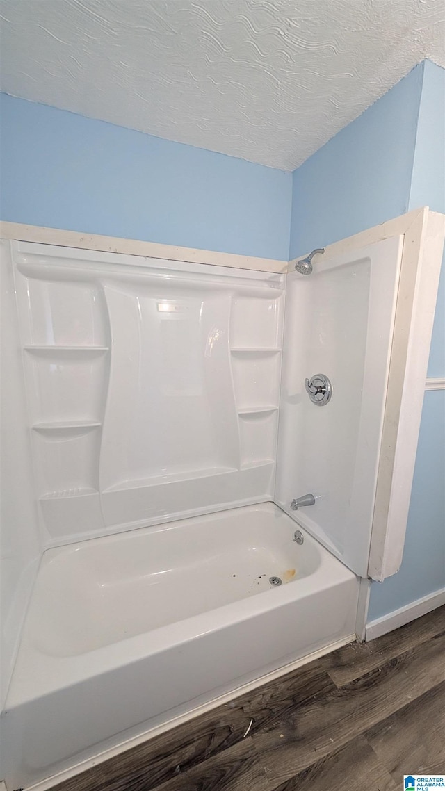 bathroom with bathing tub / shower combination, a textured ceiling, and hardwood / wood-style flooring