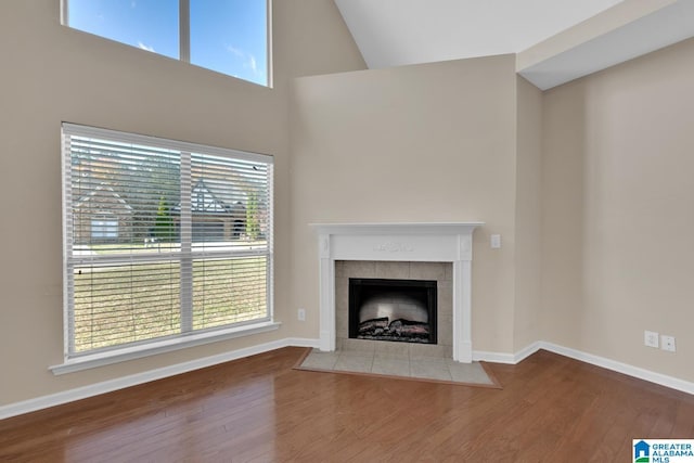 unfurnished living room featuring a tile fireplace, plenty of natural light, and hardwood / wood-style flooring