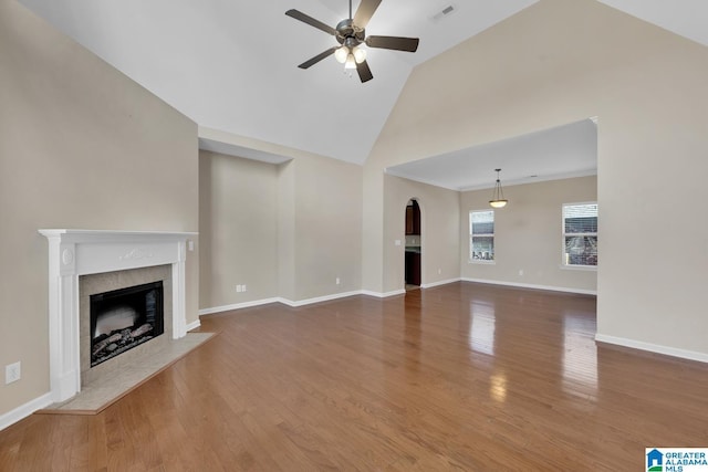 unfurnished living room with a tile fireplace, wood-type flooring, ceiling fan, and lofted ceiling