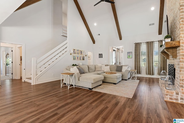 living room featuring dark hardwood / wood-style flooring, high vaulted ceiling, beamed ceiling, and a brick fireplace