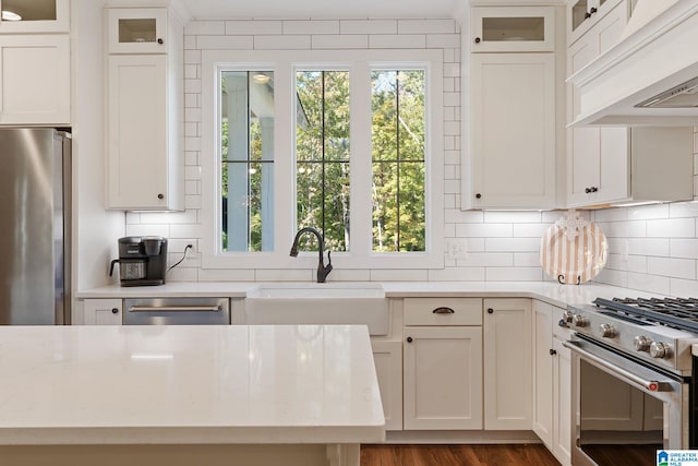 kitchen featuring appliances with stainless steel finishes, backsplash, custom exhaust hood, sink, and white cabinets